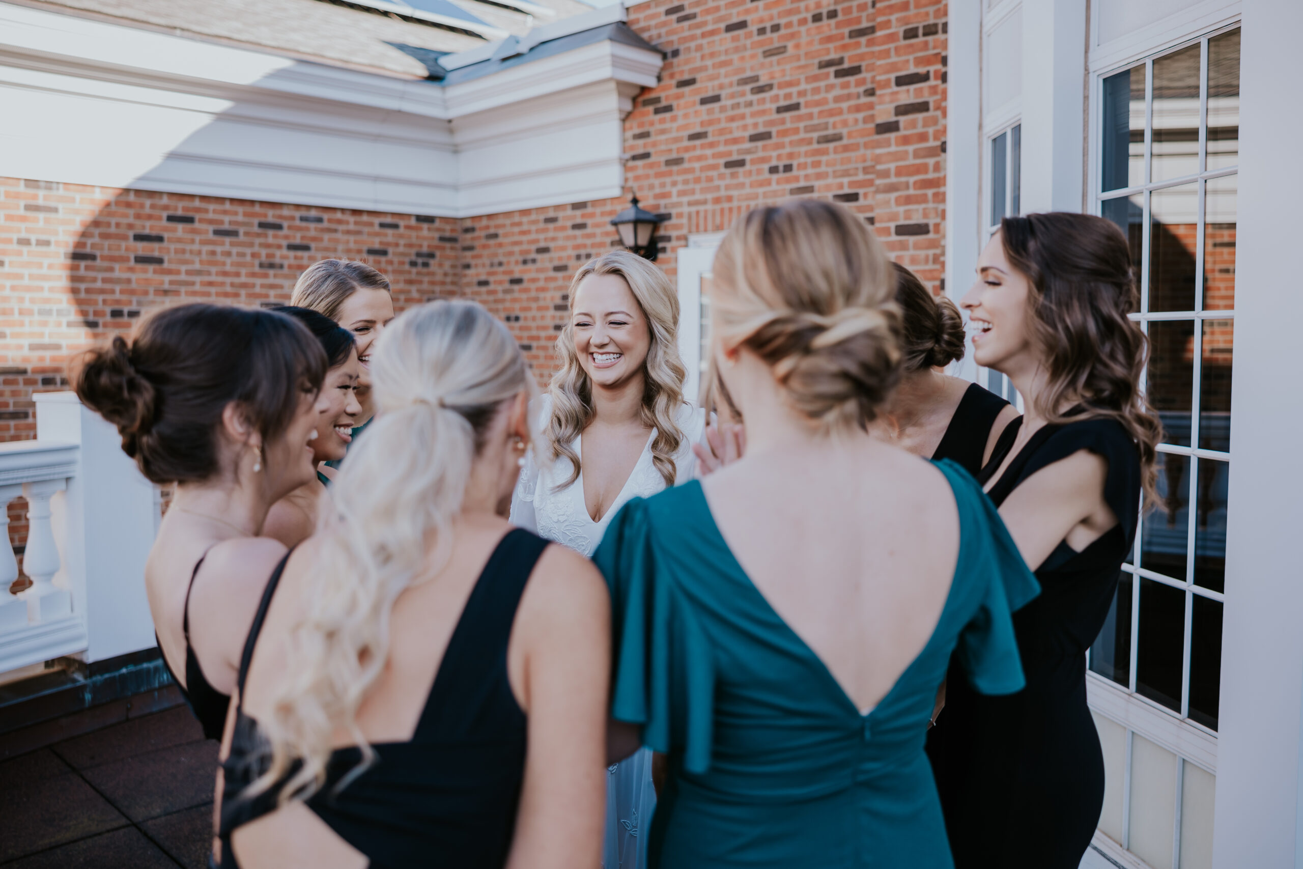 Bride surrounded by bridesmaids, laughing together before the ceremony.