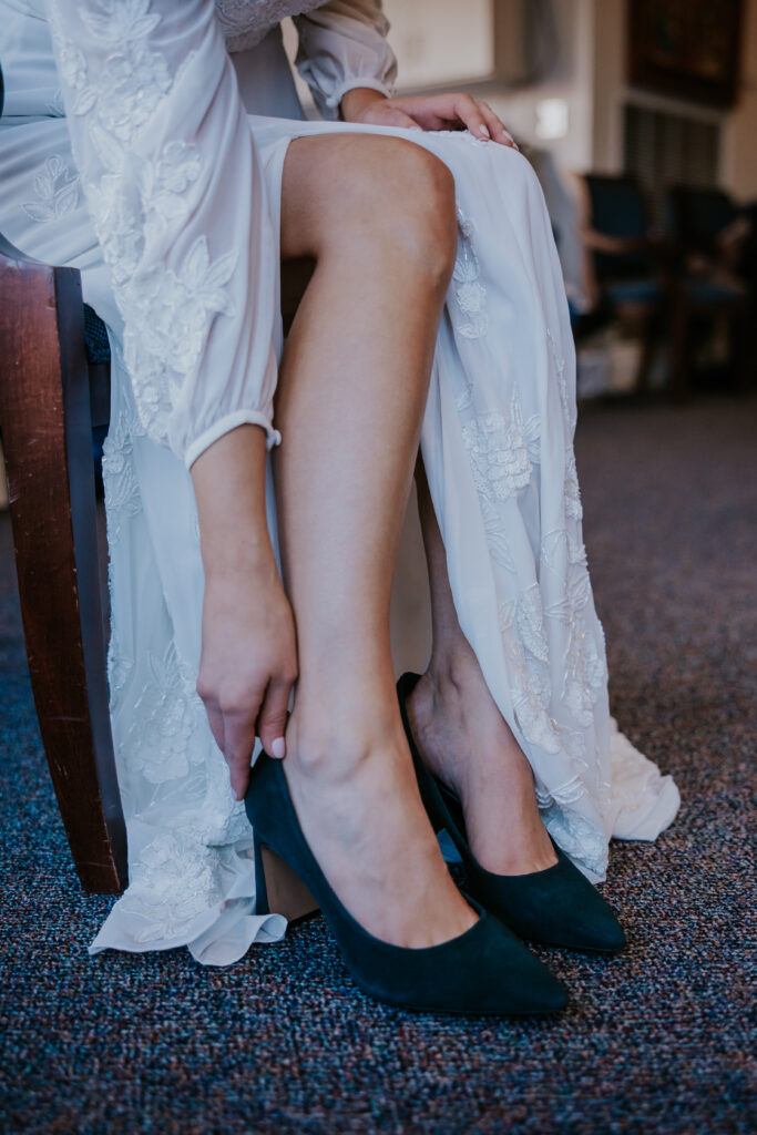 Bride putting on her dark green heels before the ceremony.