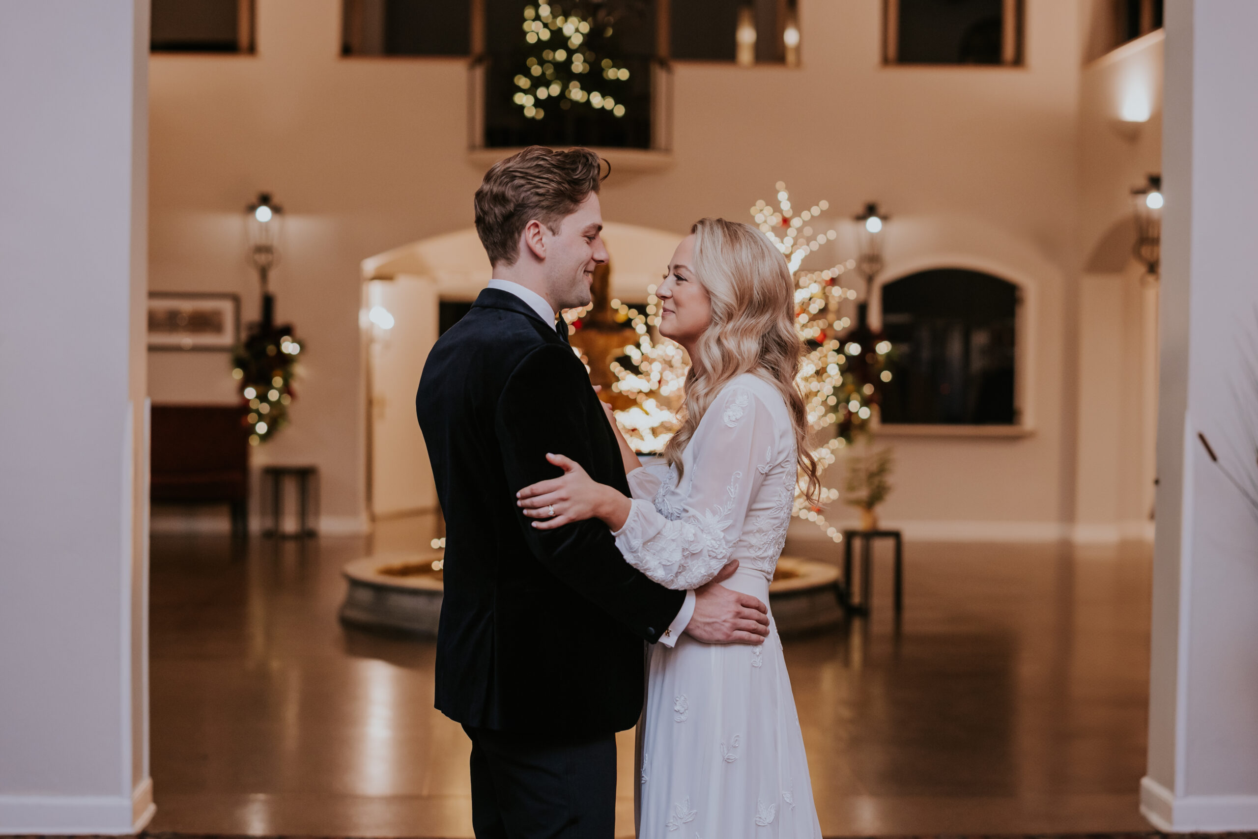 Bride and groom sharing an intimate moment indoors with glowing Christmas trees in the background, captured by a wedding photographer in Minnesota.