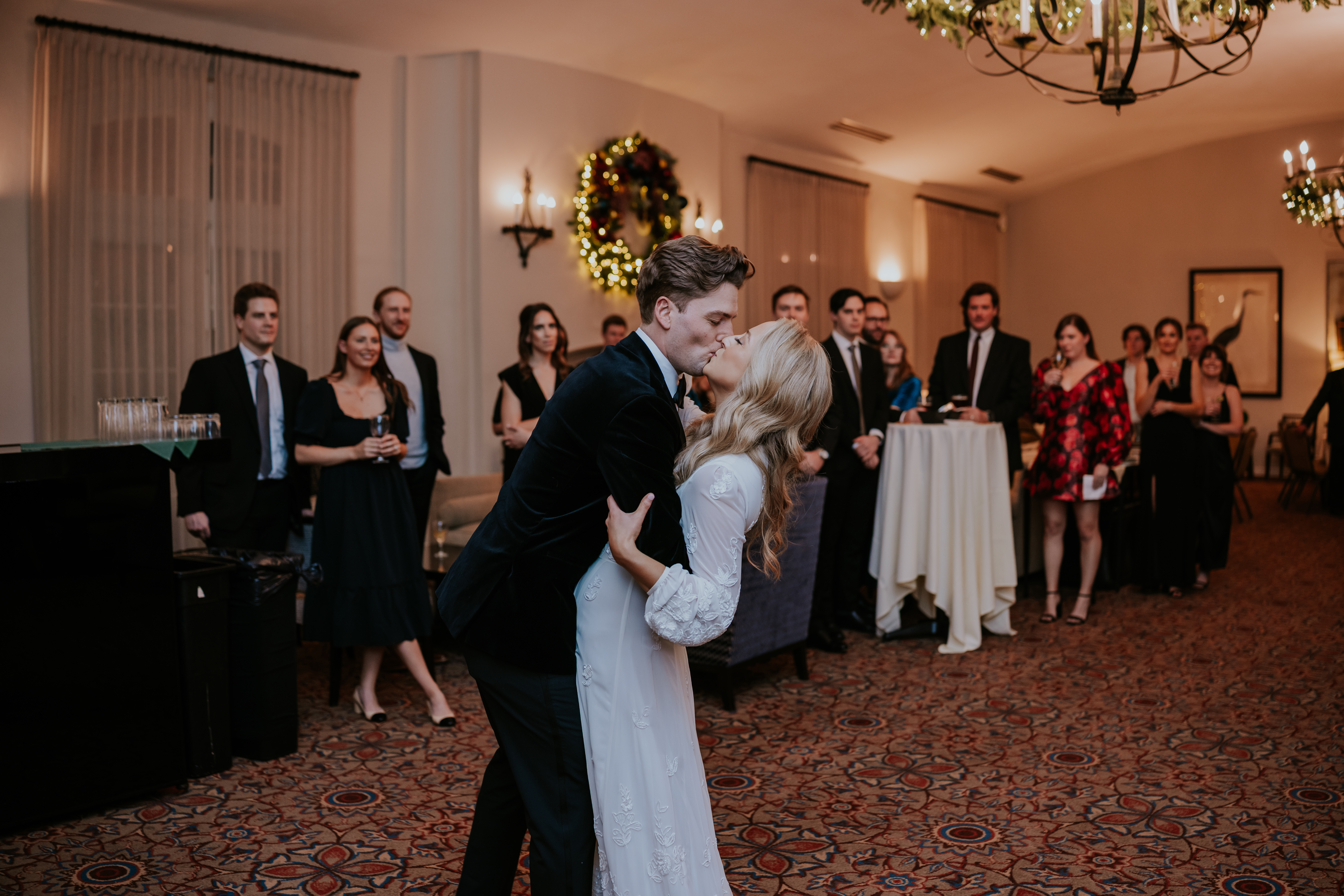 Groom dipping the bride into a kiss on the dance floor as wedding guests look on, captured by a wedding photographer in Minnesota.