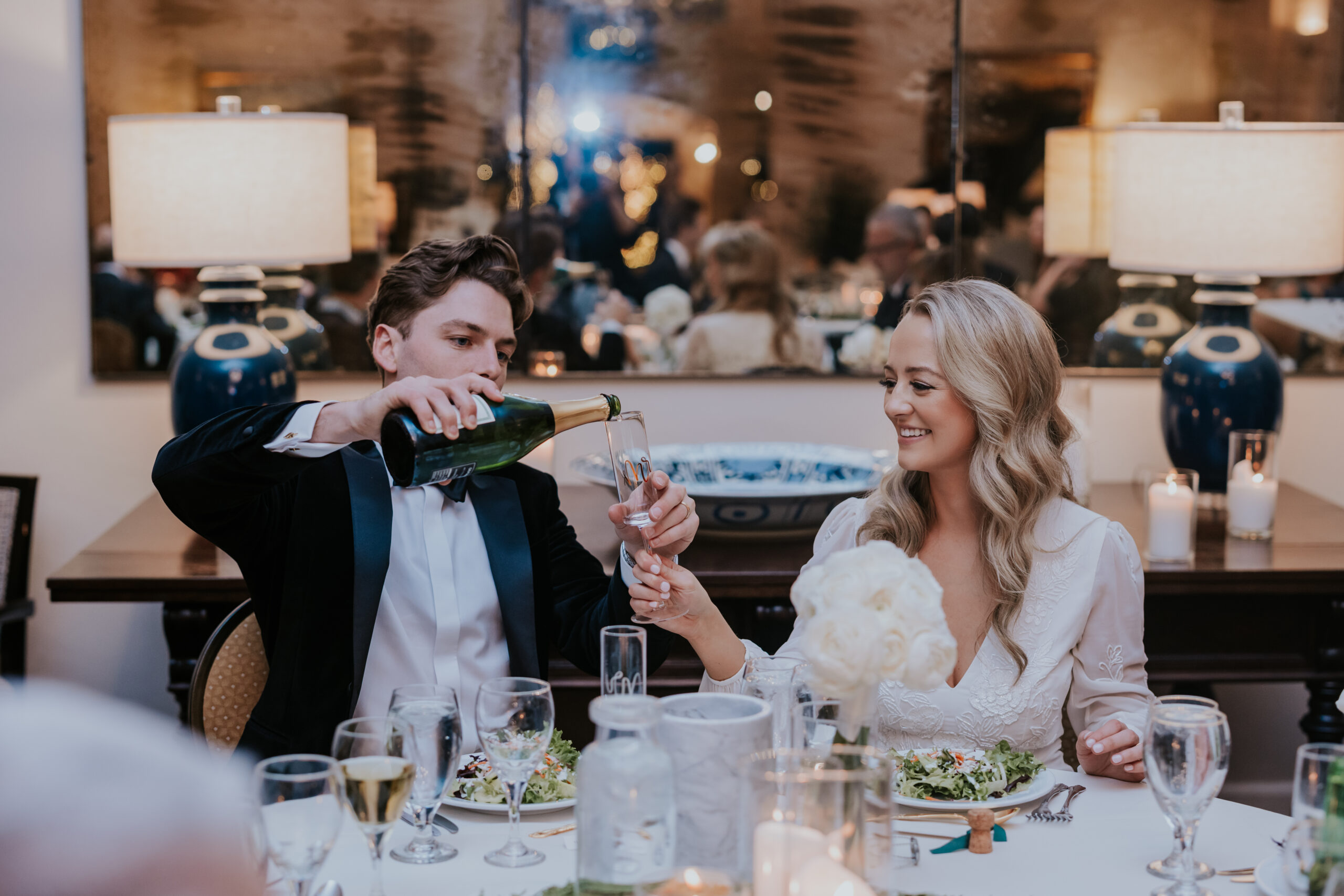 Groom pouring champagne into the bride’s glass during their dinner toast, documented by a wedding photographer in Minnesota.