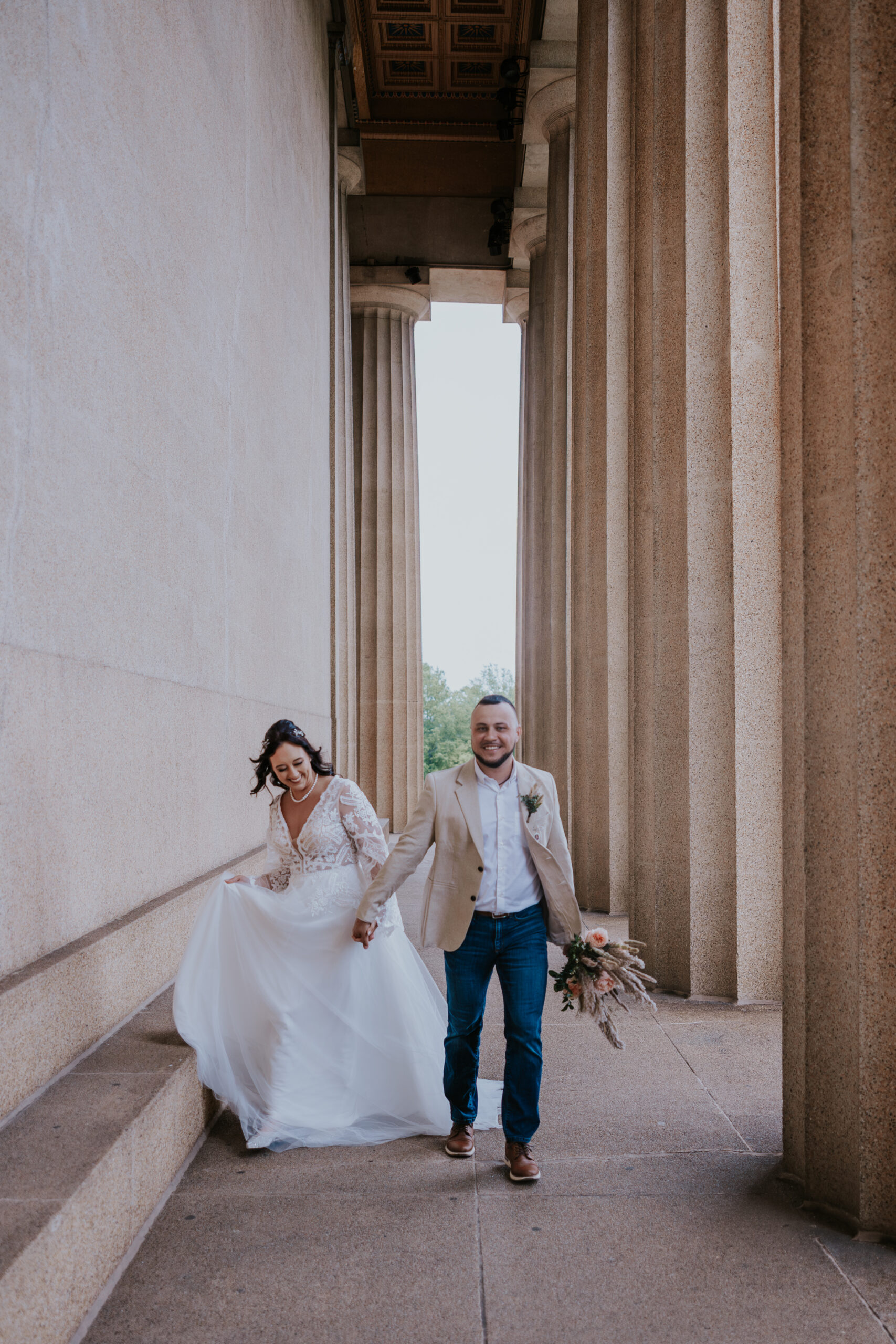 Bride and groom walking down architectural steps hand-in-hand, laughing together during their Nashville elopement session.