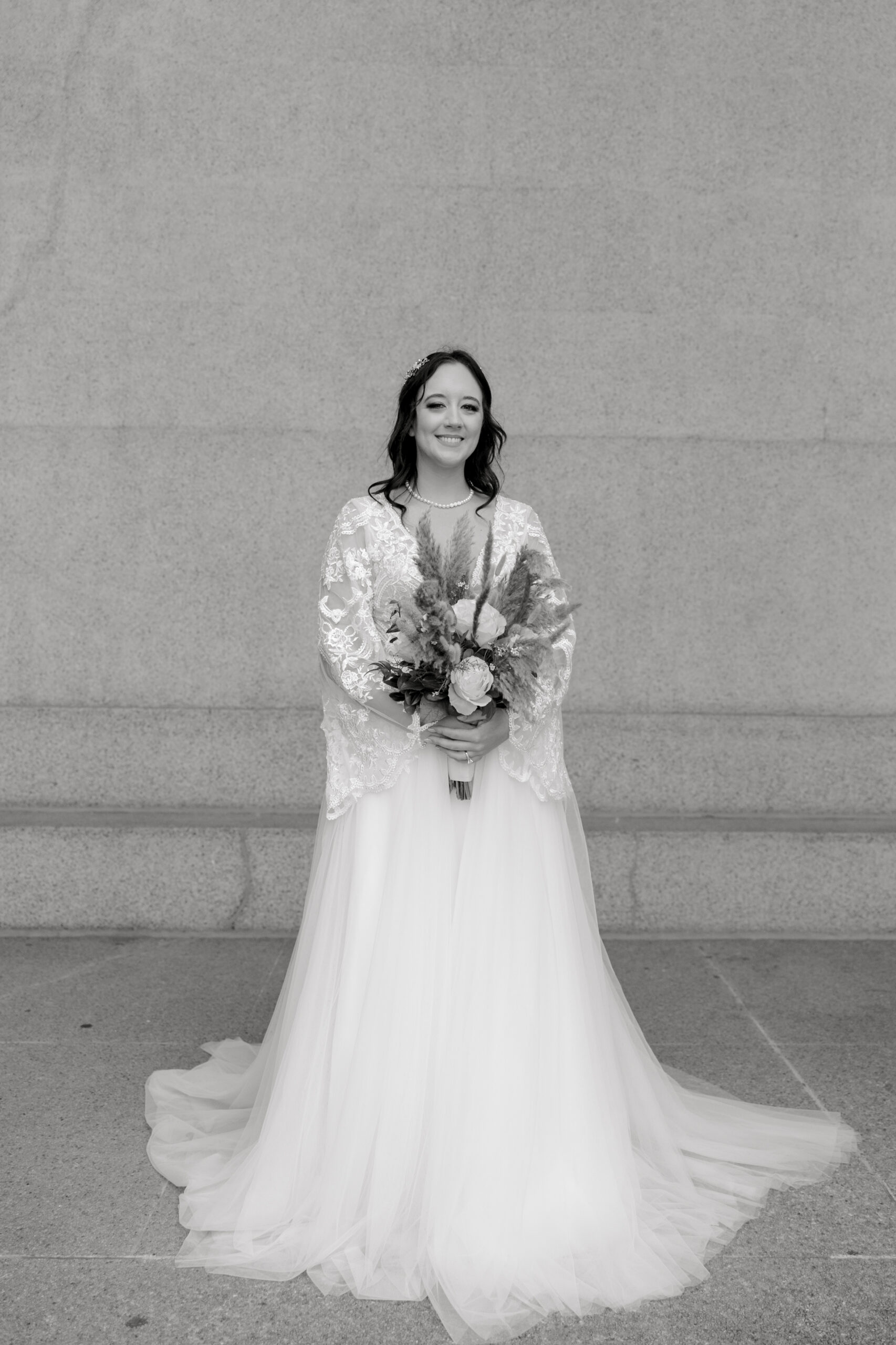 Bride in a lace wedding gown poses with her bouquet in a timeless portrait by a travel wedding photographer.