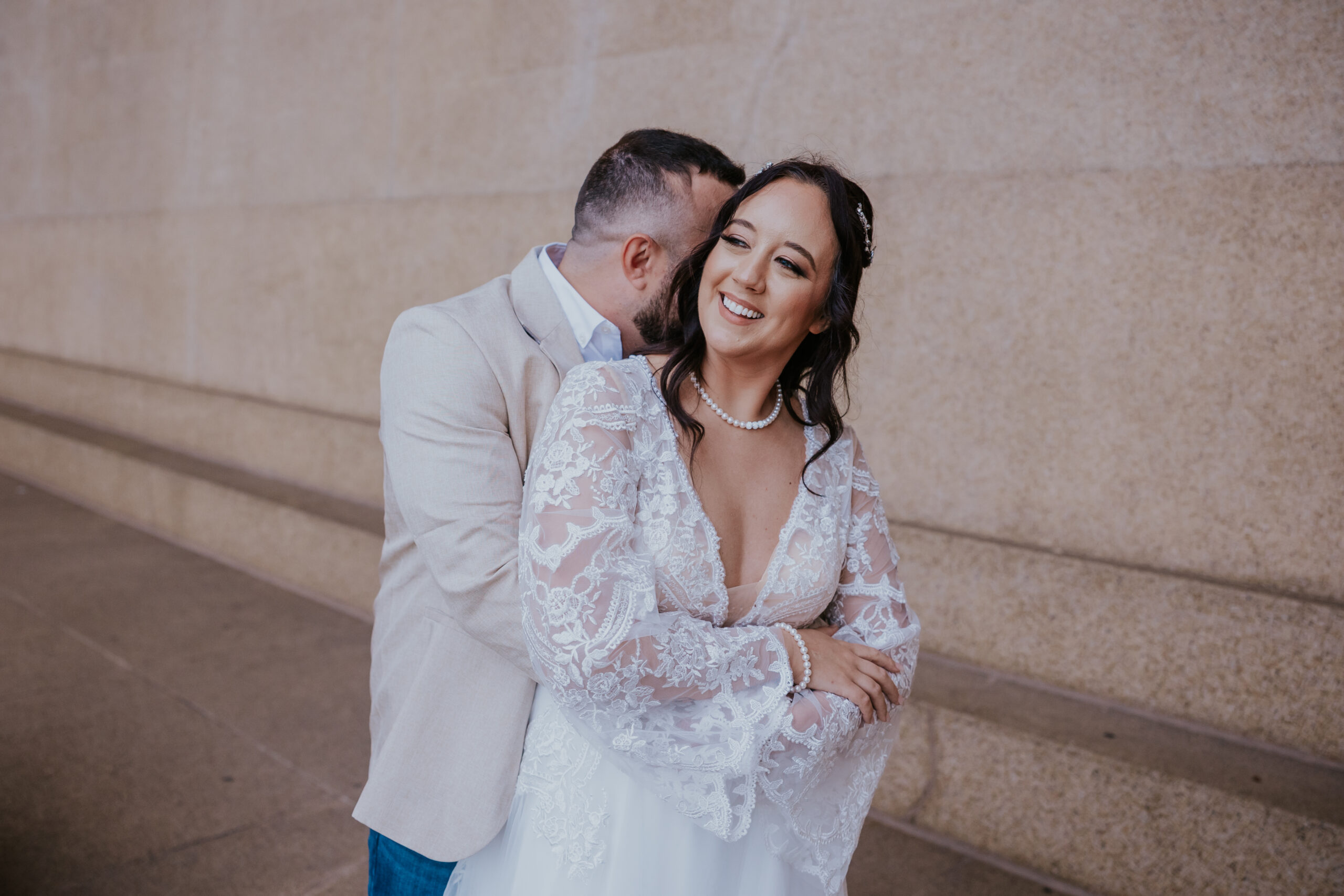 Groom embraces his smiling bride in a candid moment, captured with warmth by a travel wedding photographer.