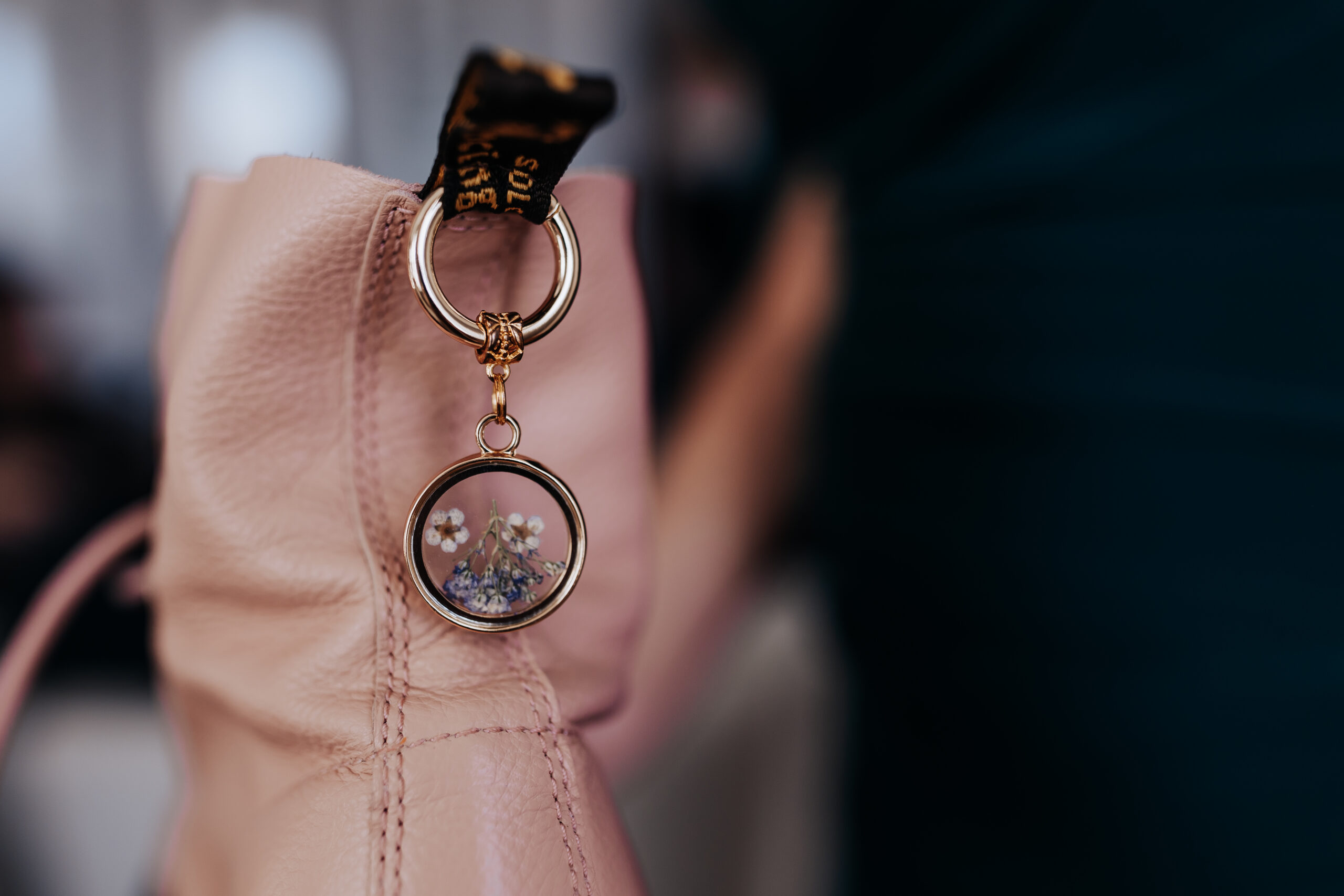 Close-up of a pressed flower keychain charm attached to a blush pink leather boot—perfect for wedding detail photos.