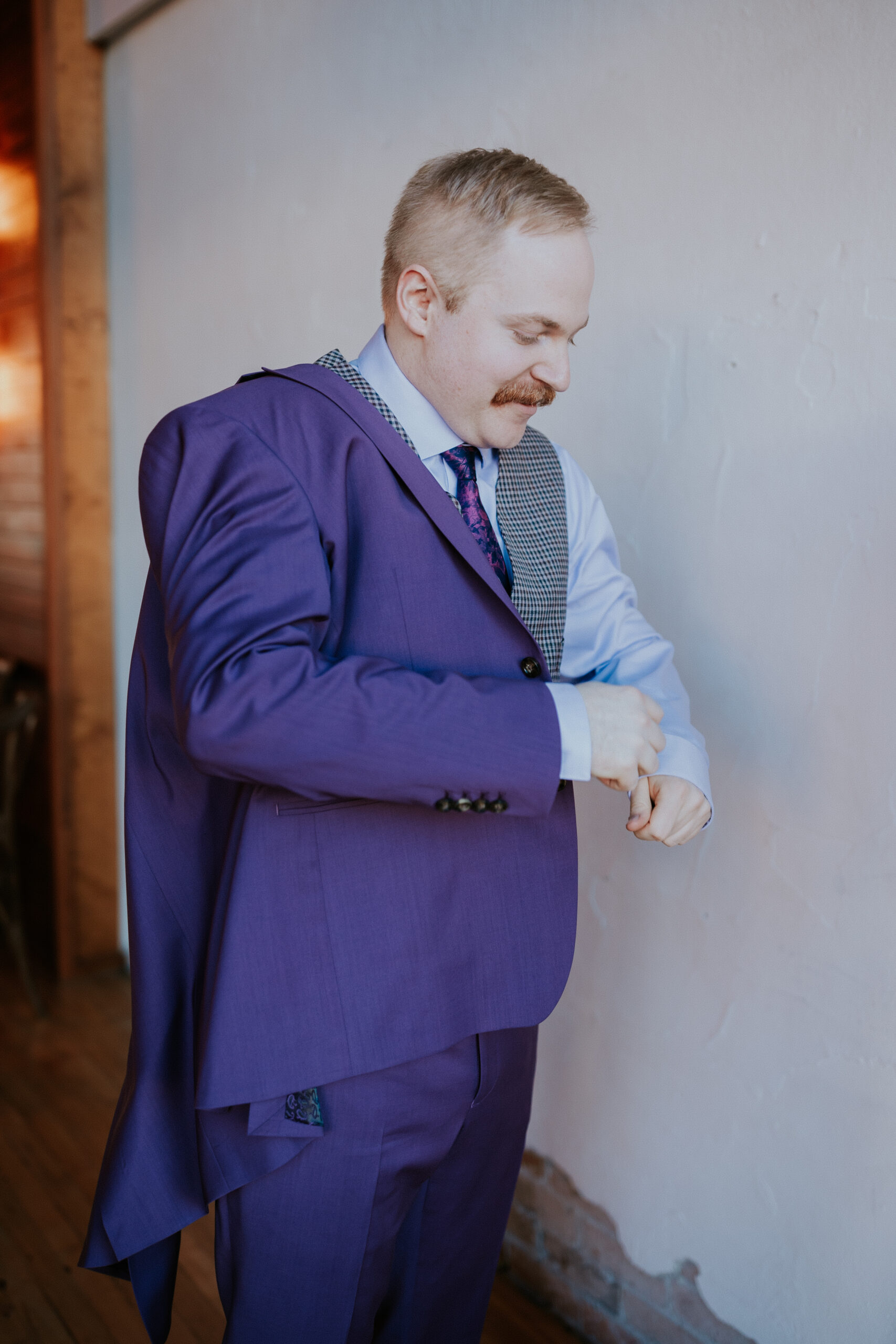 Groom putting on his purple wedding jacket, getting ready for the ceremony.