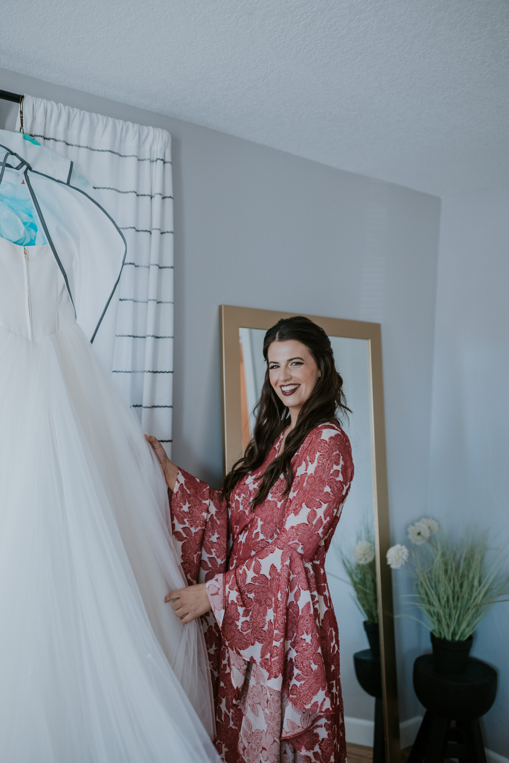 Bride holding her wedding gown and smiling, a quiet moment of excitement before getting ready.