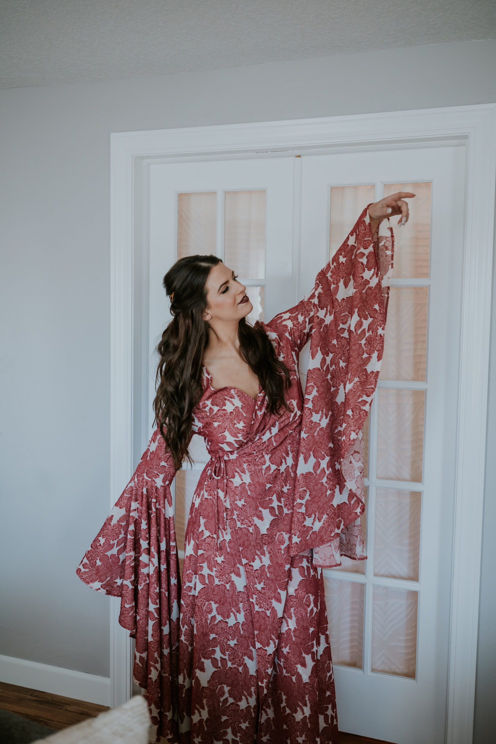 Bride smiling in her floral robe as she prepares for the wedding day with joy and calm.
