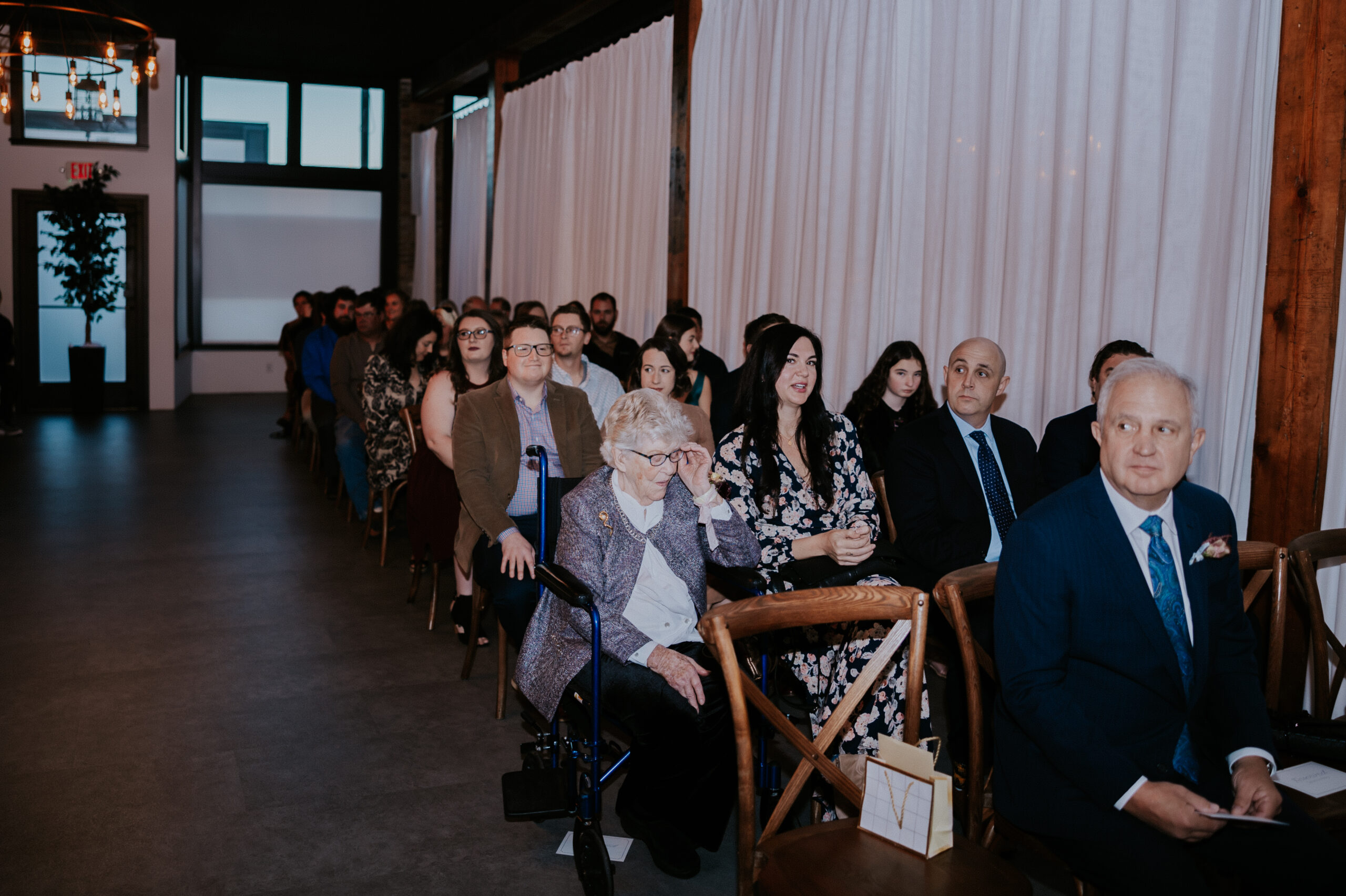 Wedding guests seated and waiting for the ceremony to begin in a modern indoor venue.