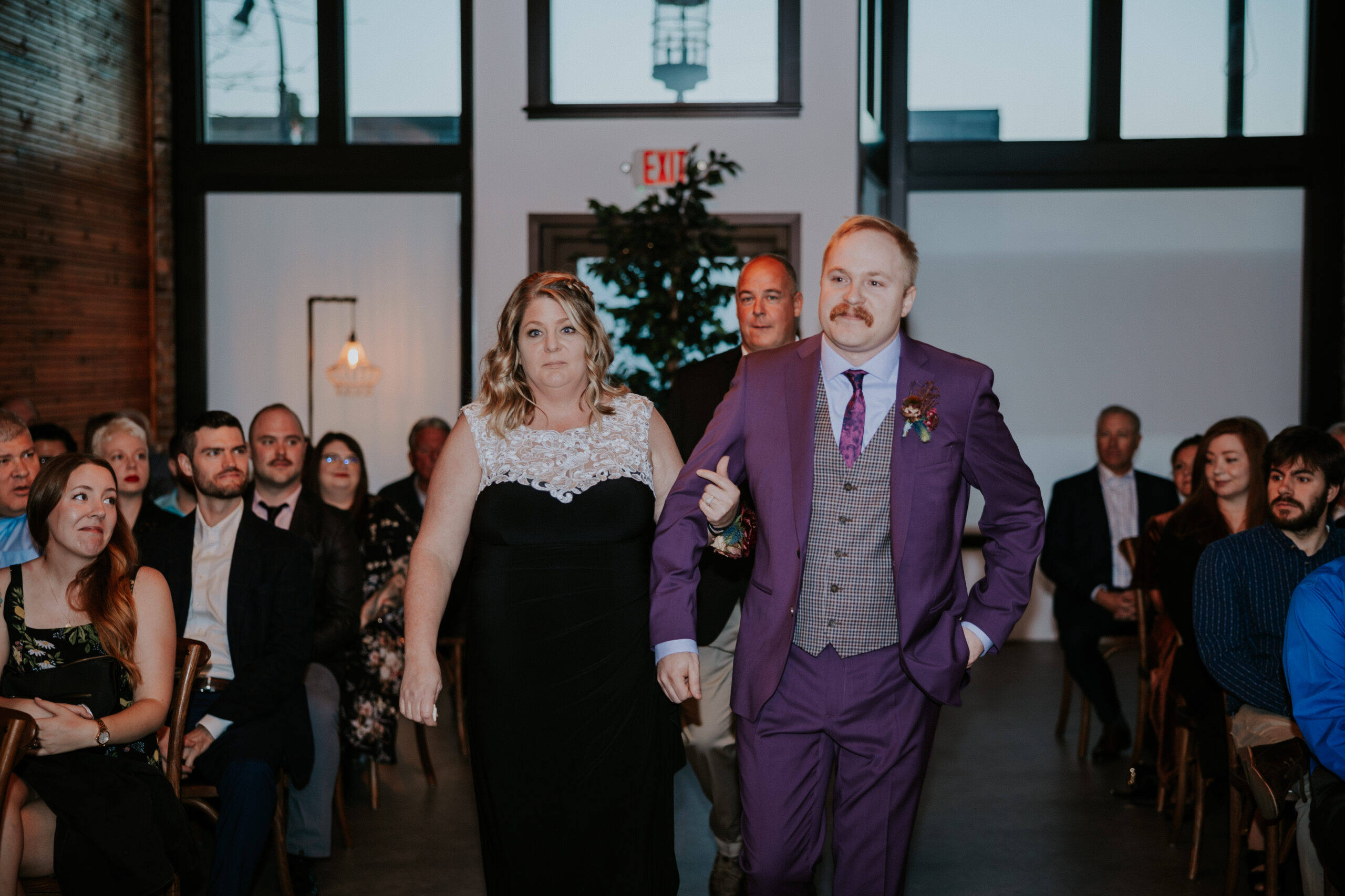 Groom walking down the aisle arm-in-arm with a family member, emotional moments captured before the ceremony.