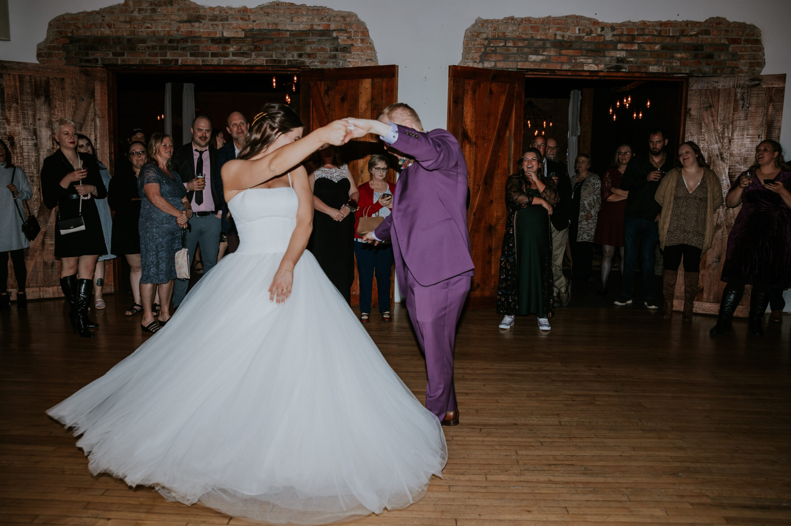 The bride twirling during her first dance, the train of her dress fanned out across the hardwood floor.