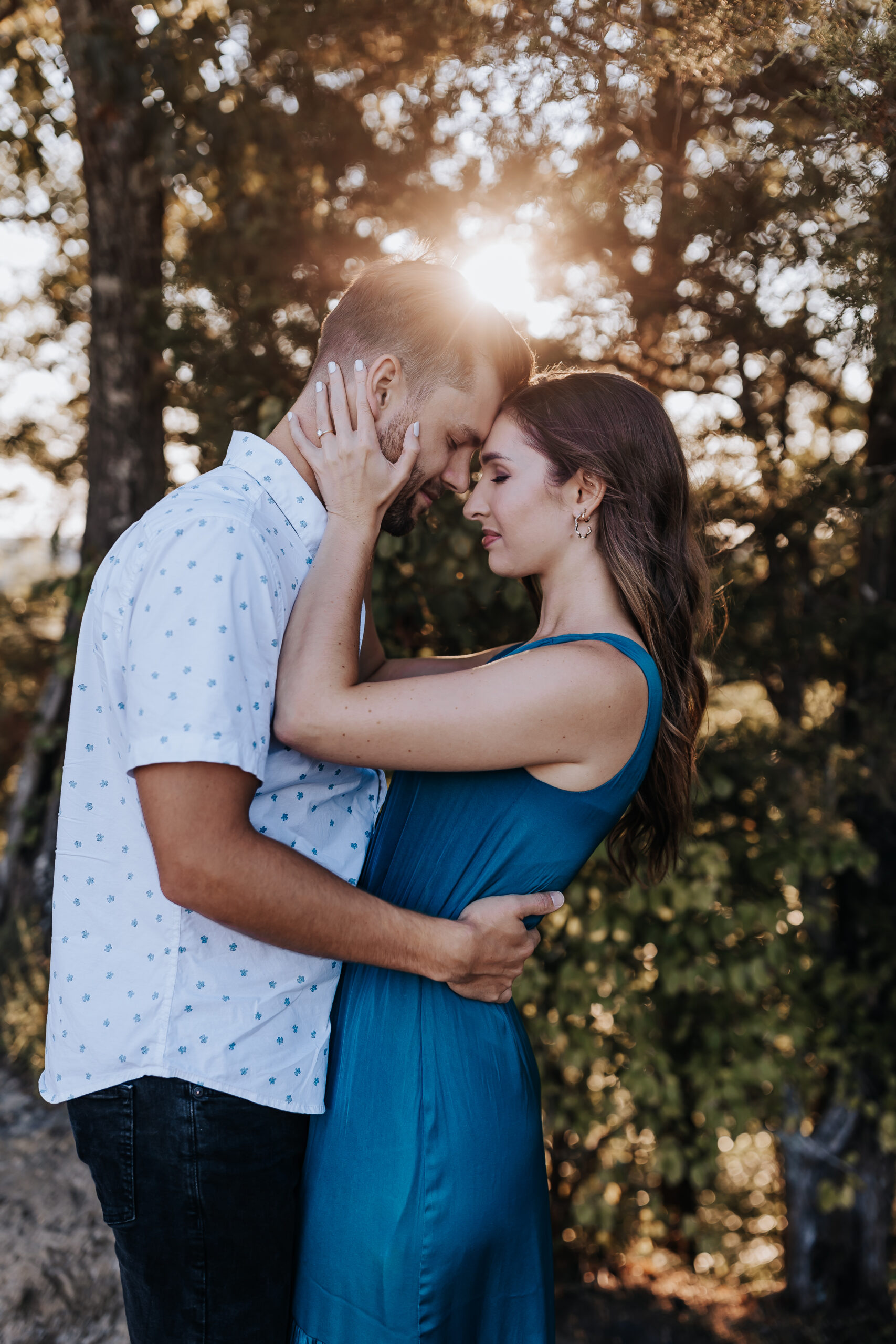 A couple shares a tender forehead touch with golden light behind them, captured during their session with a Nashville engagement photographer.