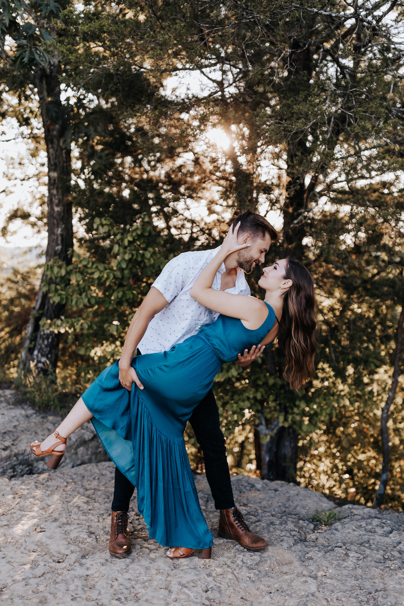 A man dips his fiancée in a playful, romantic pose surrounded by trees and golden sunlight, captured by a Nashville engagement photographer.