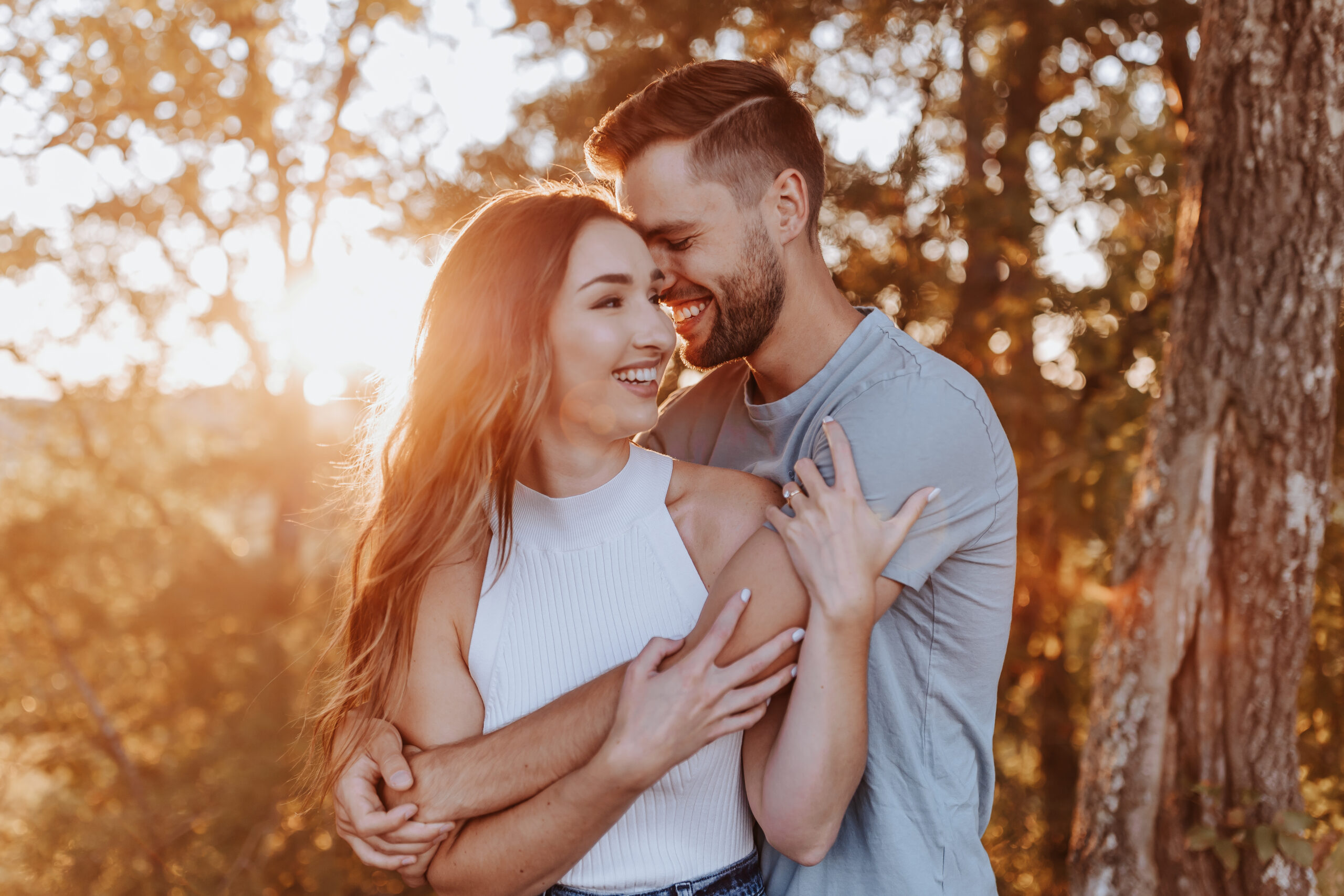 A playful couple shares a laugh in golden-hour light, arms wrapped around each other during their session with a Nashville engagement photographer.