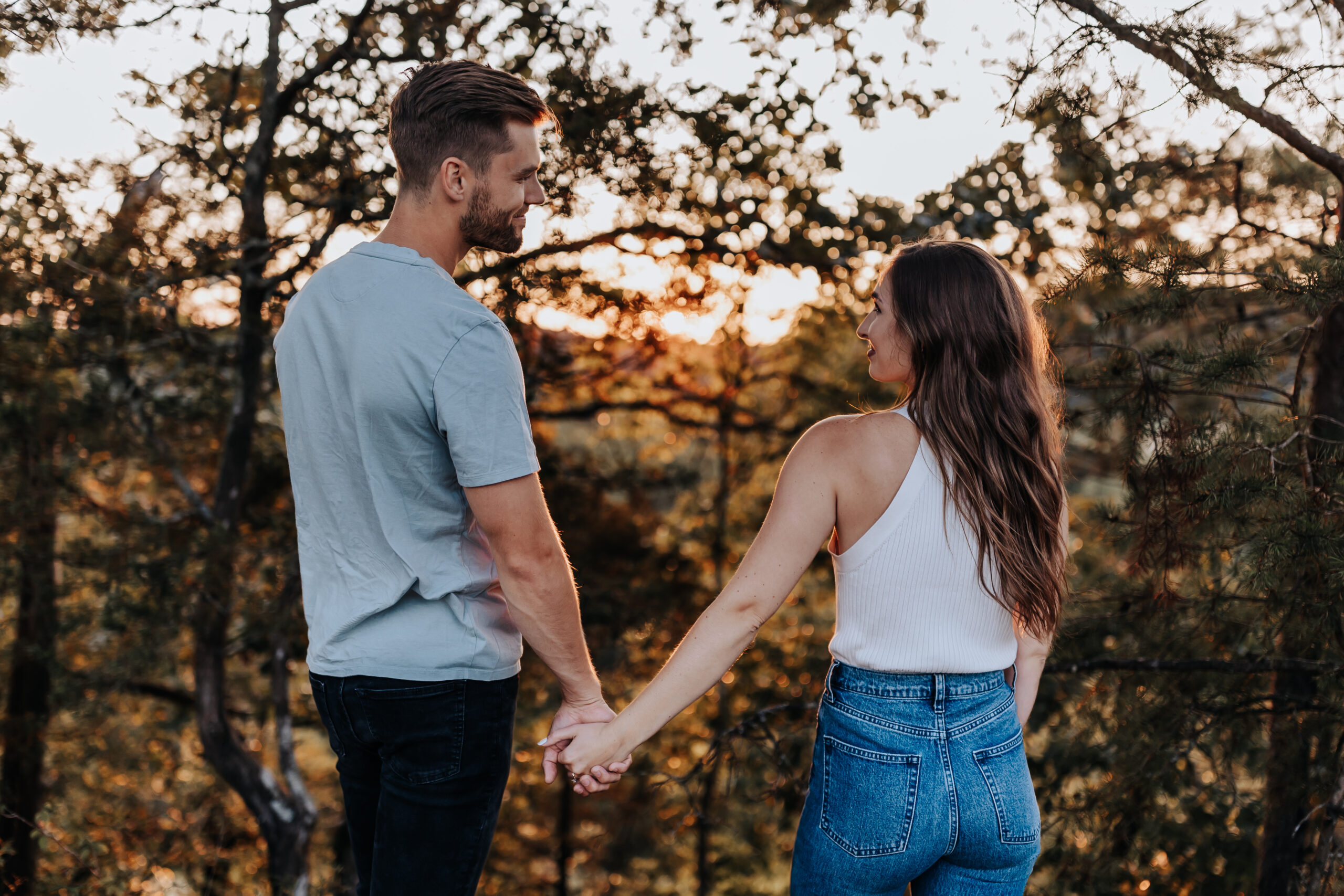 A romantic moment as a couple holds hands and gazes at each other while the sun sets behind them during a Nashville engagement photographer session.