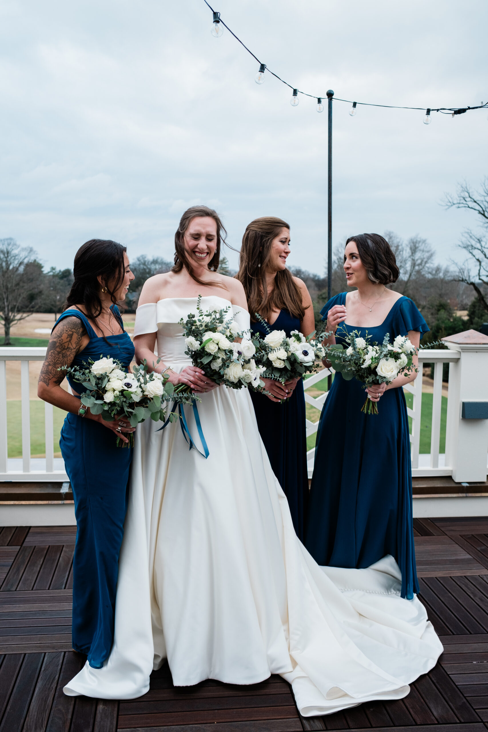 The bride and her bridesmaids share a joyful moment outdoors, beautifully documented in our wedding photographer packages.