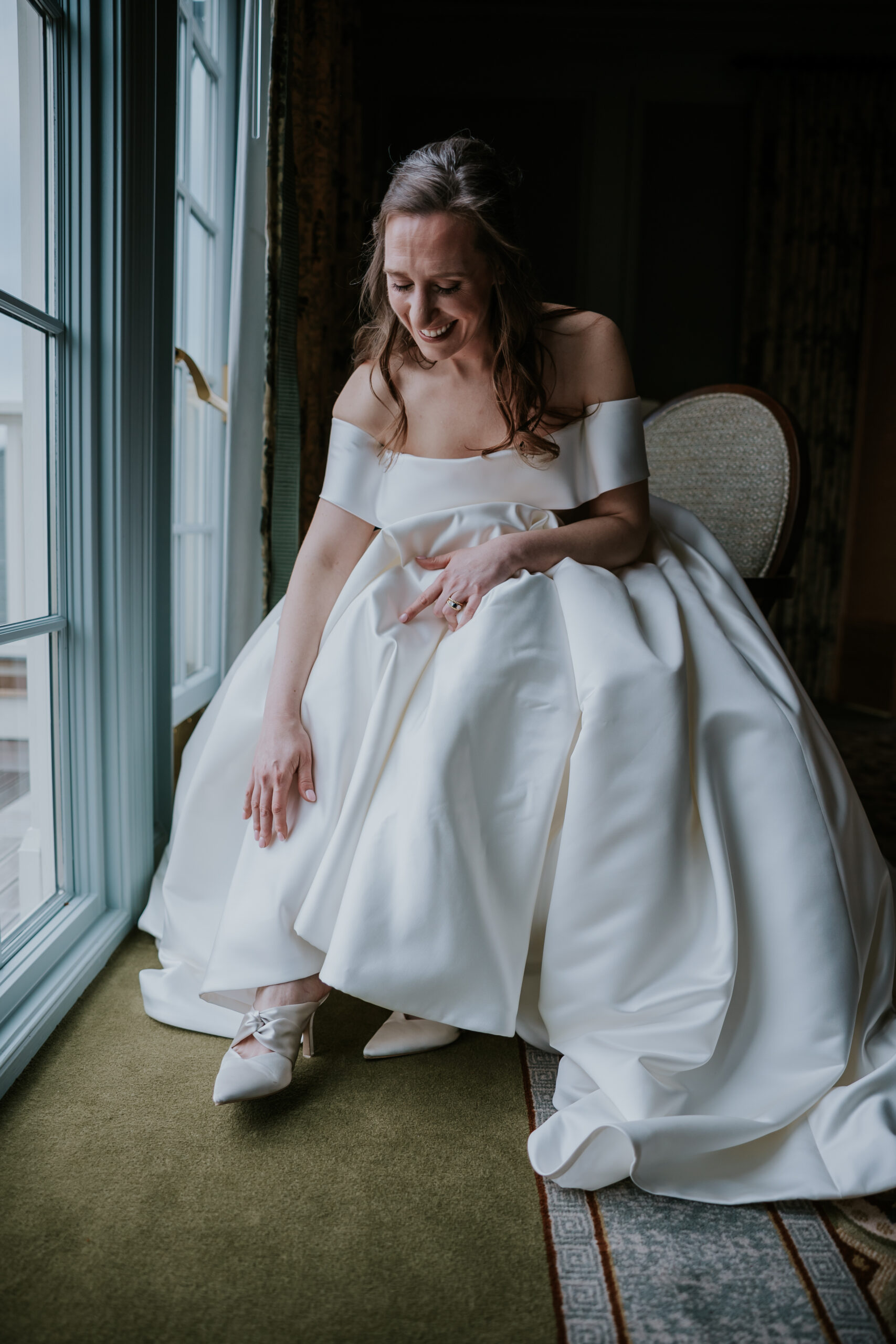 The bride beams as she slips on her heels, a joyful prep moment often featured in full-day wedding photographer packages.