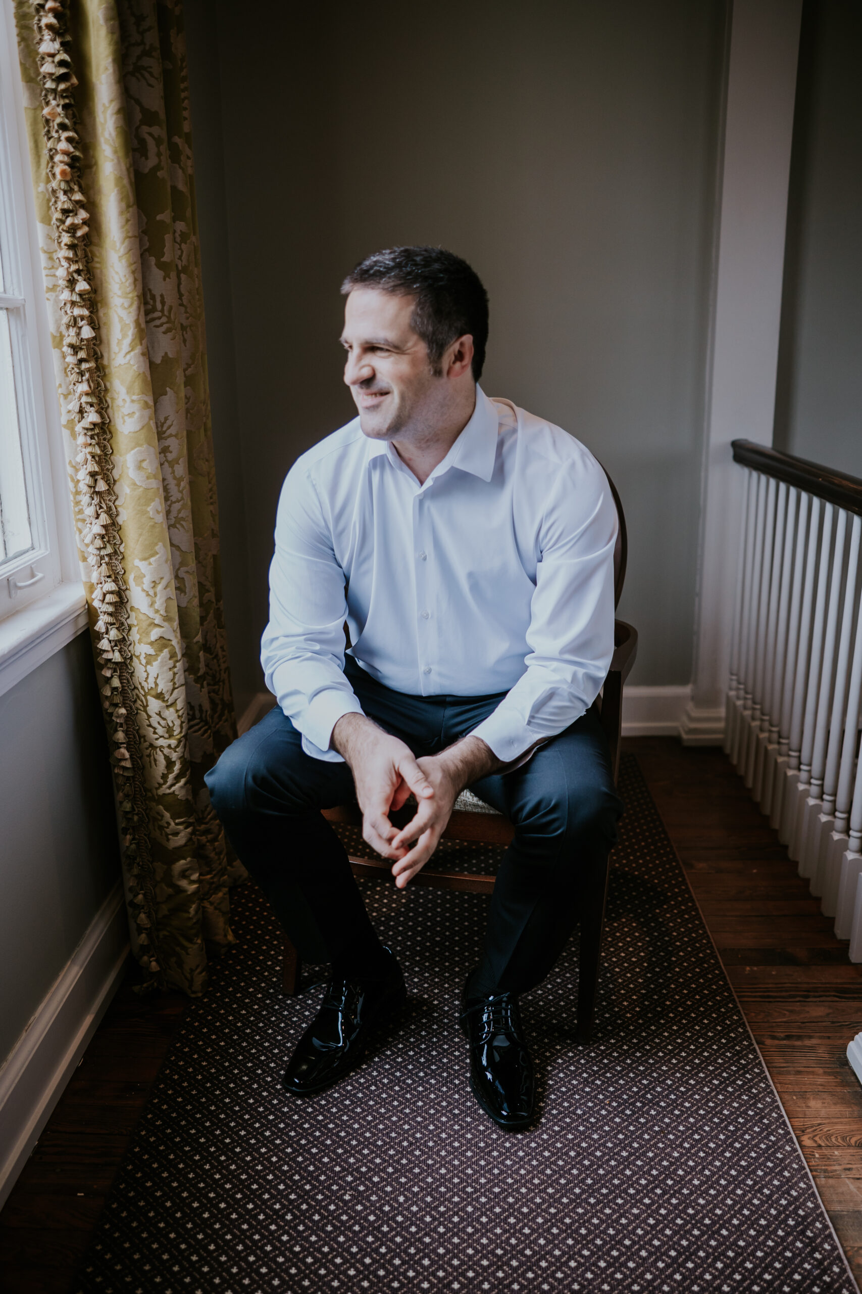 Groom takes a quiet moment by the window before the ceremony—a relaxed portrait included in many wedding photographer packages.