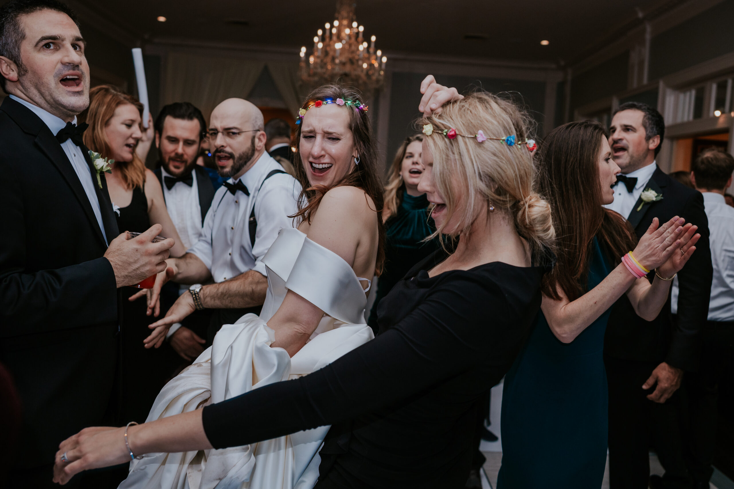 The bride laughs and dances with friends during a high-energy wedding reception—candid fun like this is a must-have in wedding photographer packages.