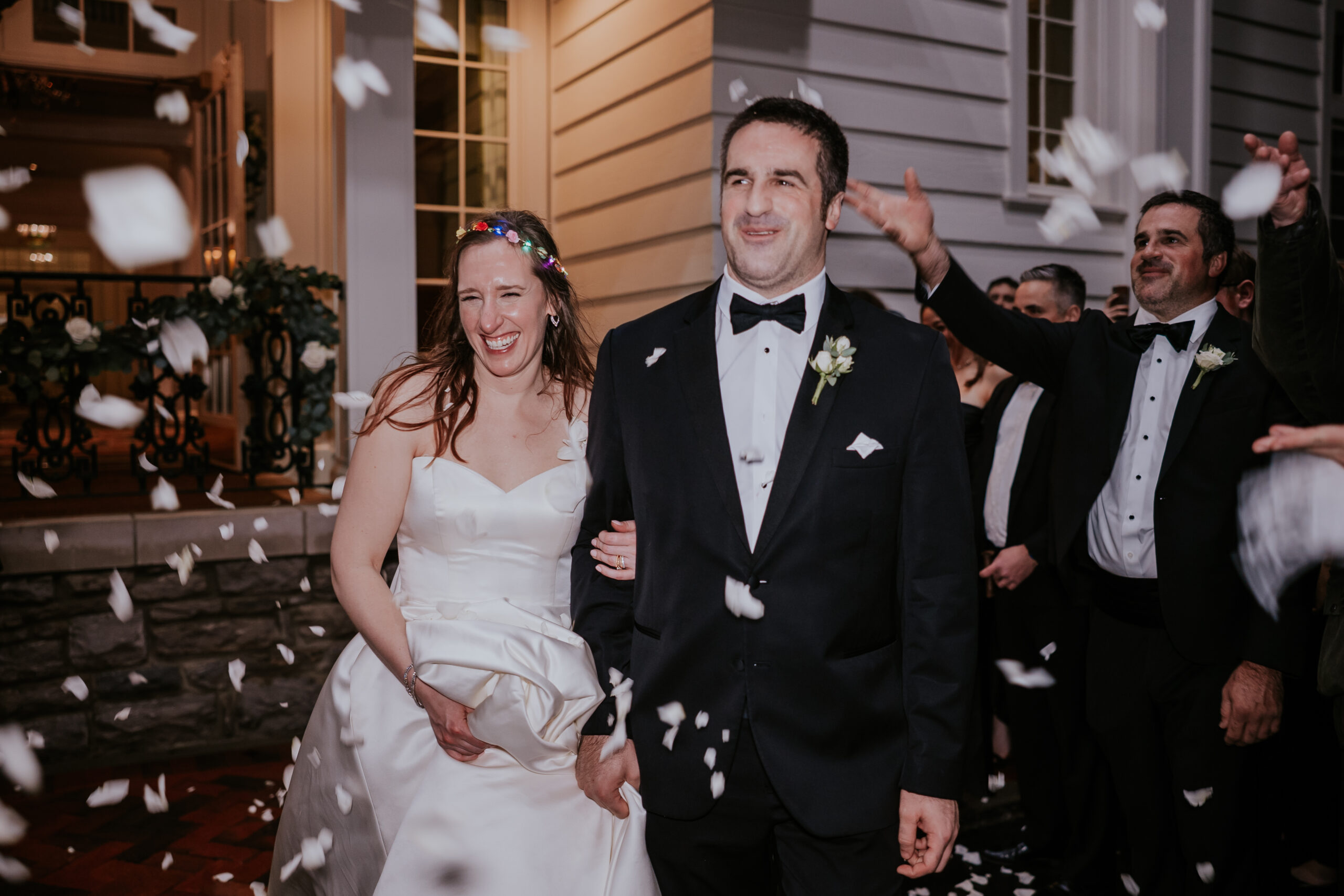 Newlyweds laugh together as they walk through a cascade of flower petals—an unforgettable moment captured as part of our wedding photographer packages.