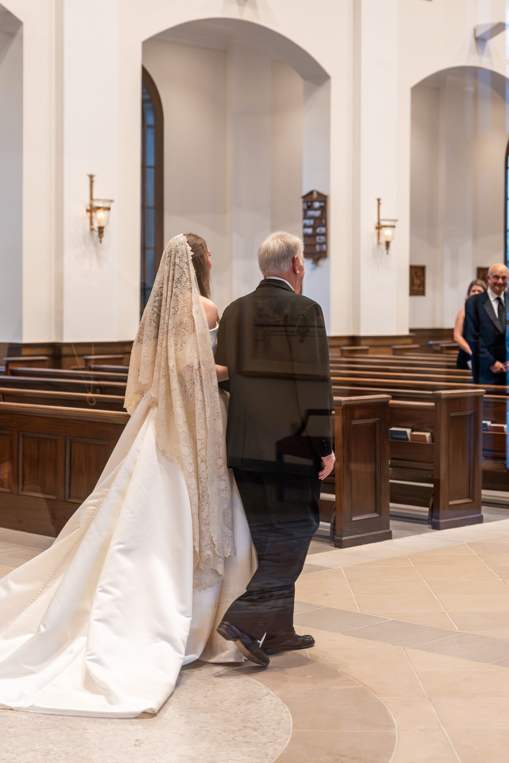 Bride and her father walk arm in arm down the church aisle, an emotional moment beautifully preserved through wedding photographer packages.