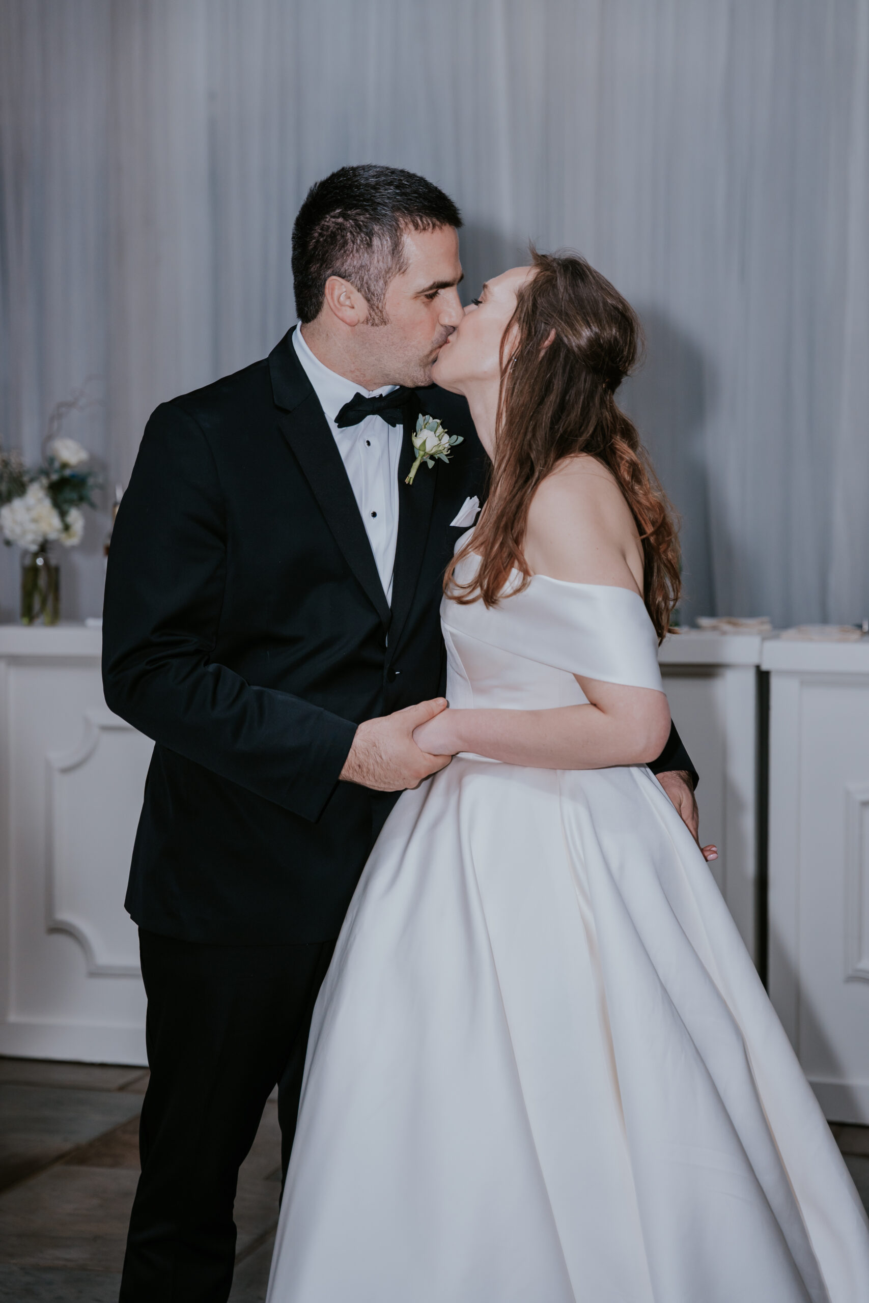 Romantic close-up of the bride and groom sharing a sweet kiss in front of the bar during their celebration.