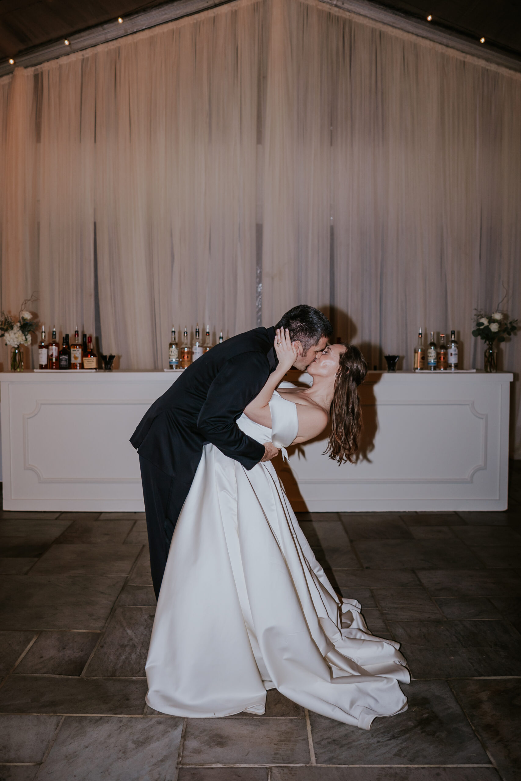 A cinematic dip-and-kiss moment in front of the bar, perfectly posed and featured in deluxe wedding photographer packages.