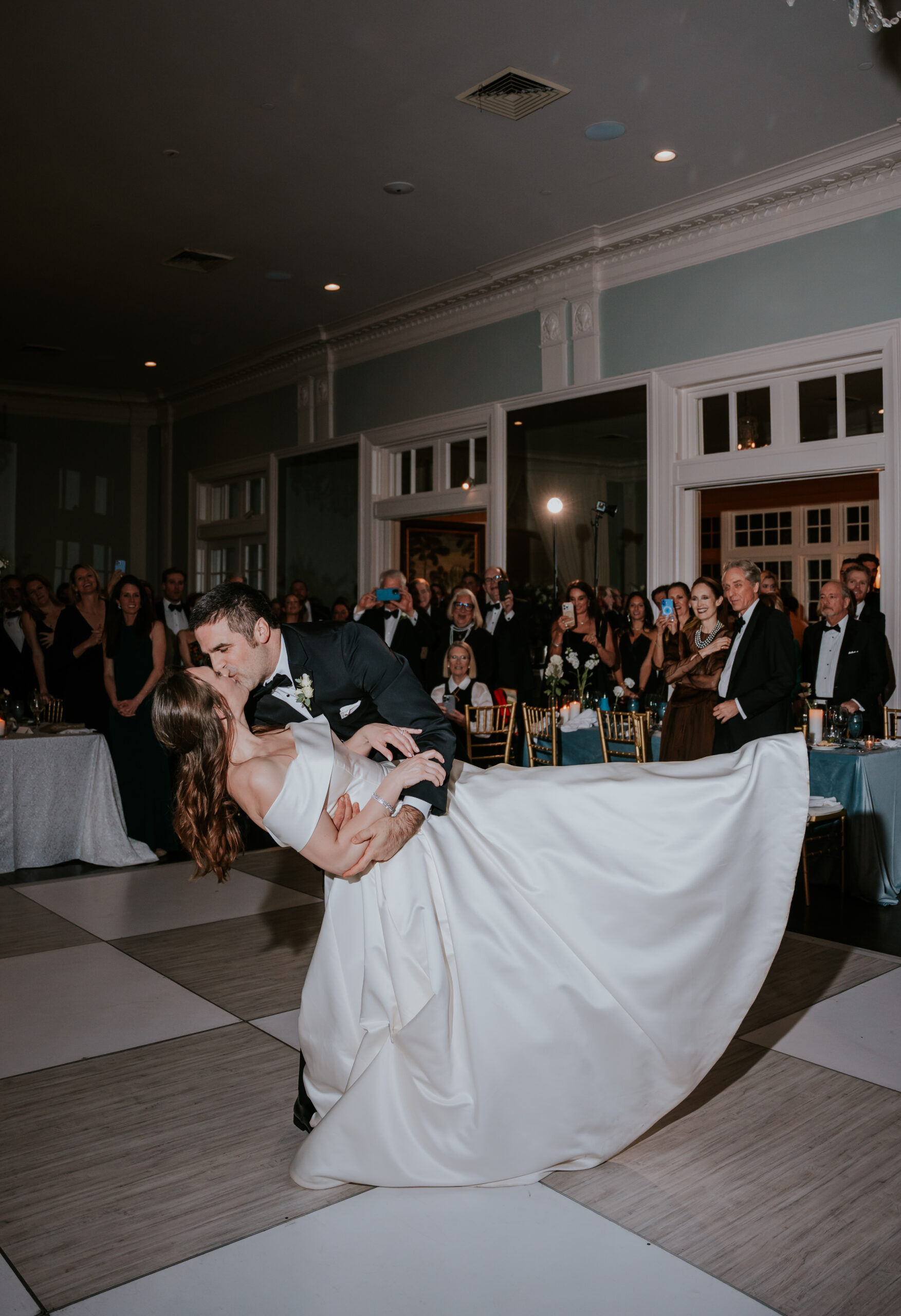 The groom leans into a dip and kiss during their first dance, a signature moment included in many wedding photographer packages.
