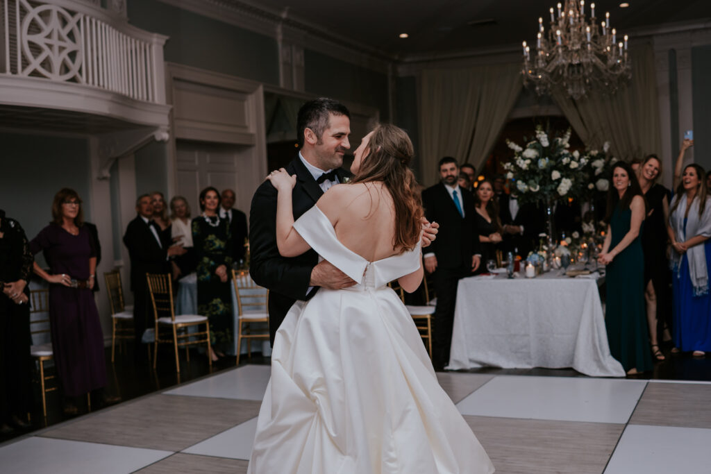 The couple twirls across the dance floor beneath a glowing chandelier—a classic highlight captured in premium wedding photographer packages.