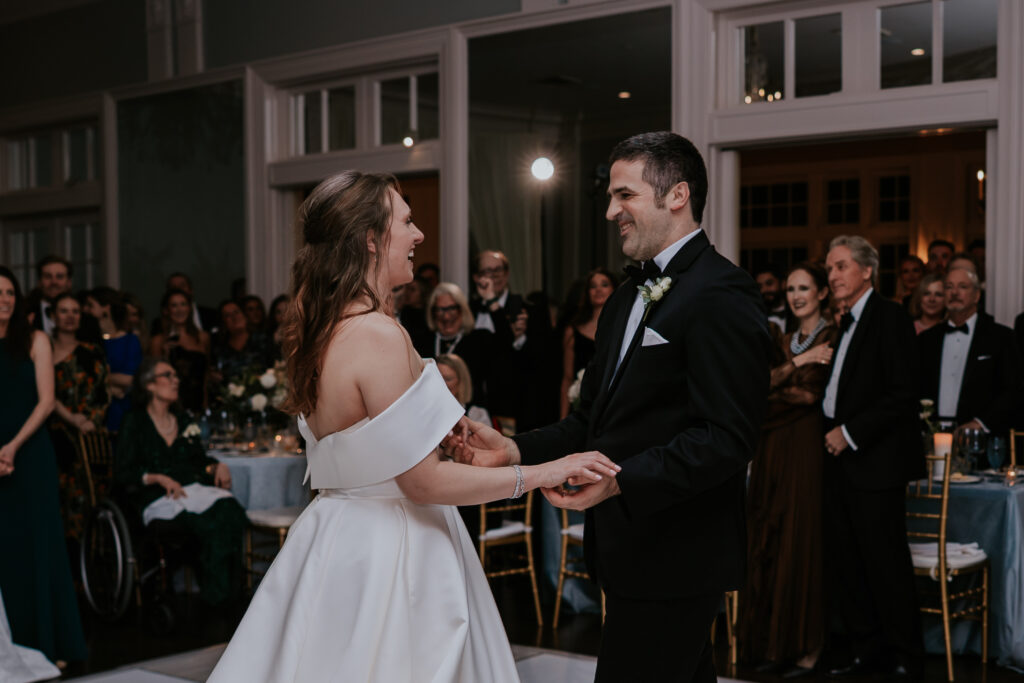 The newlyweds share a joyful look while dancing in front of their guests, surrounded by love and cheers.