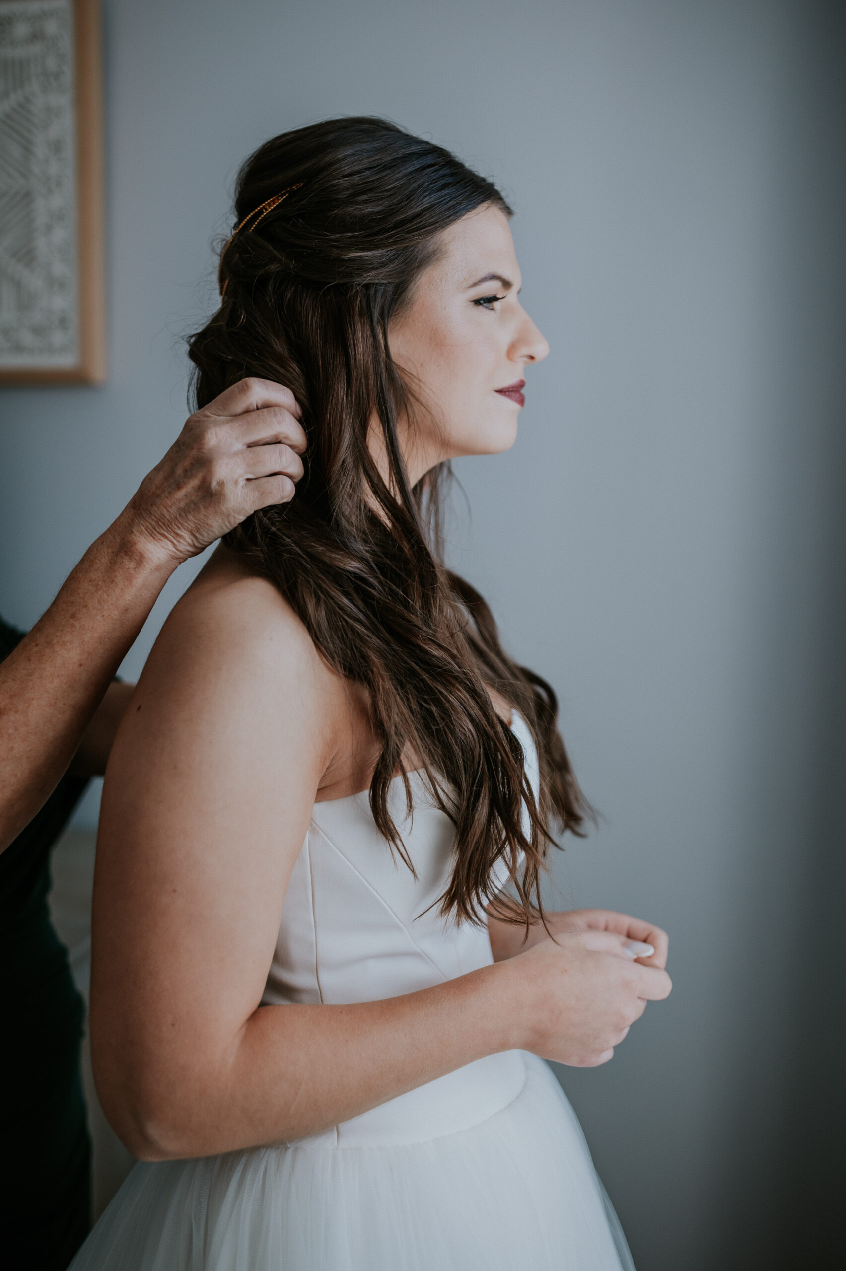 Final hair touches are made as the bride gets ready, showcasing her elegant loose waves and strapless gown.
