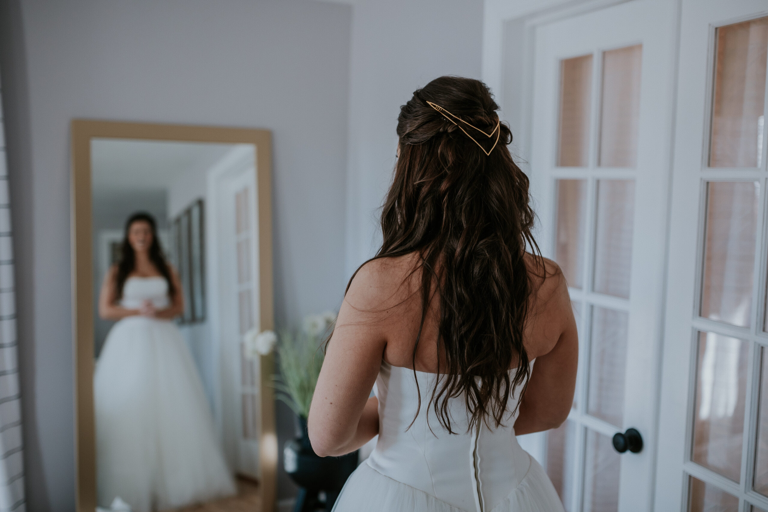 A reflection shot of the bride looking at herself in the mirror, showing off her simple and romantic hairstyle.