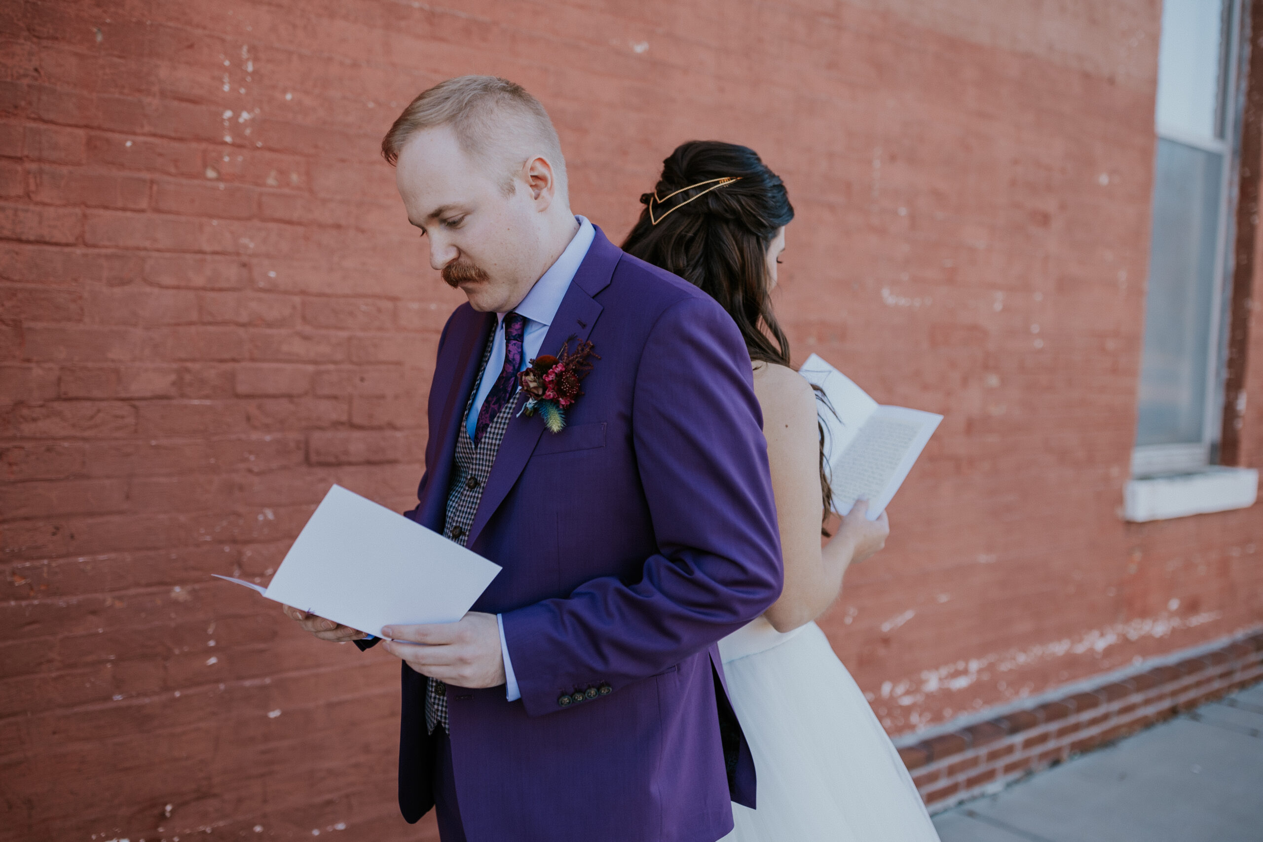 The bride and groom stand back-to-back reading private vows, soaking in the emotion of their wedding in Minnesota.