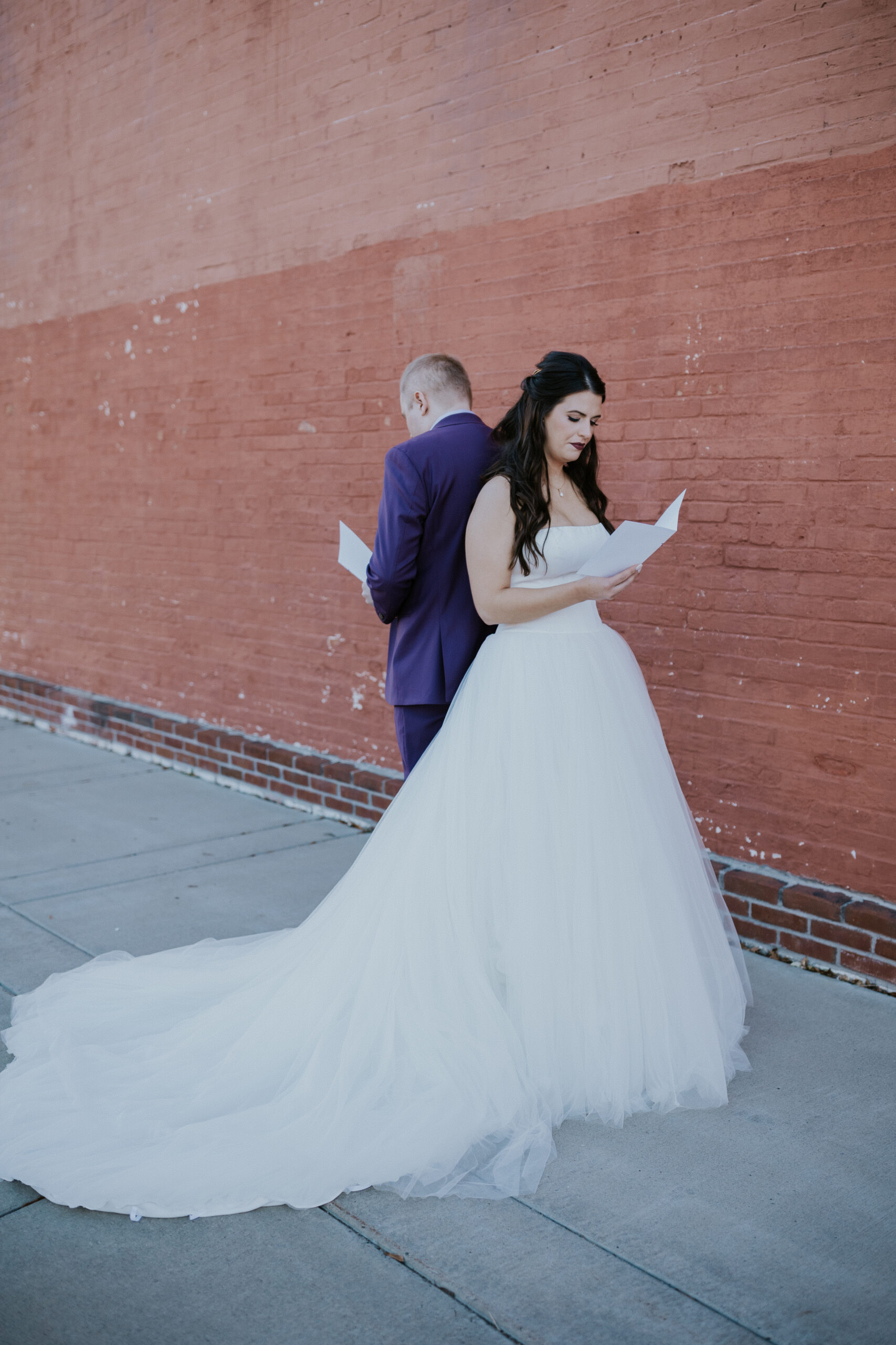 Bride and groom stand back-to-back reading private vows during an emotional first look at their wedding in Minnesota.