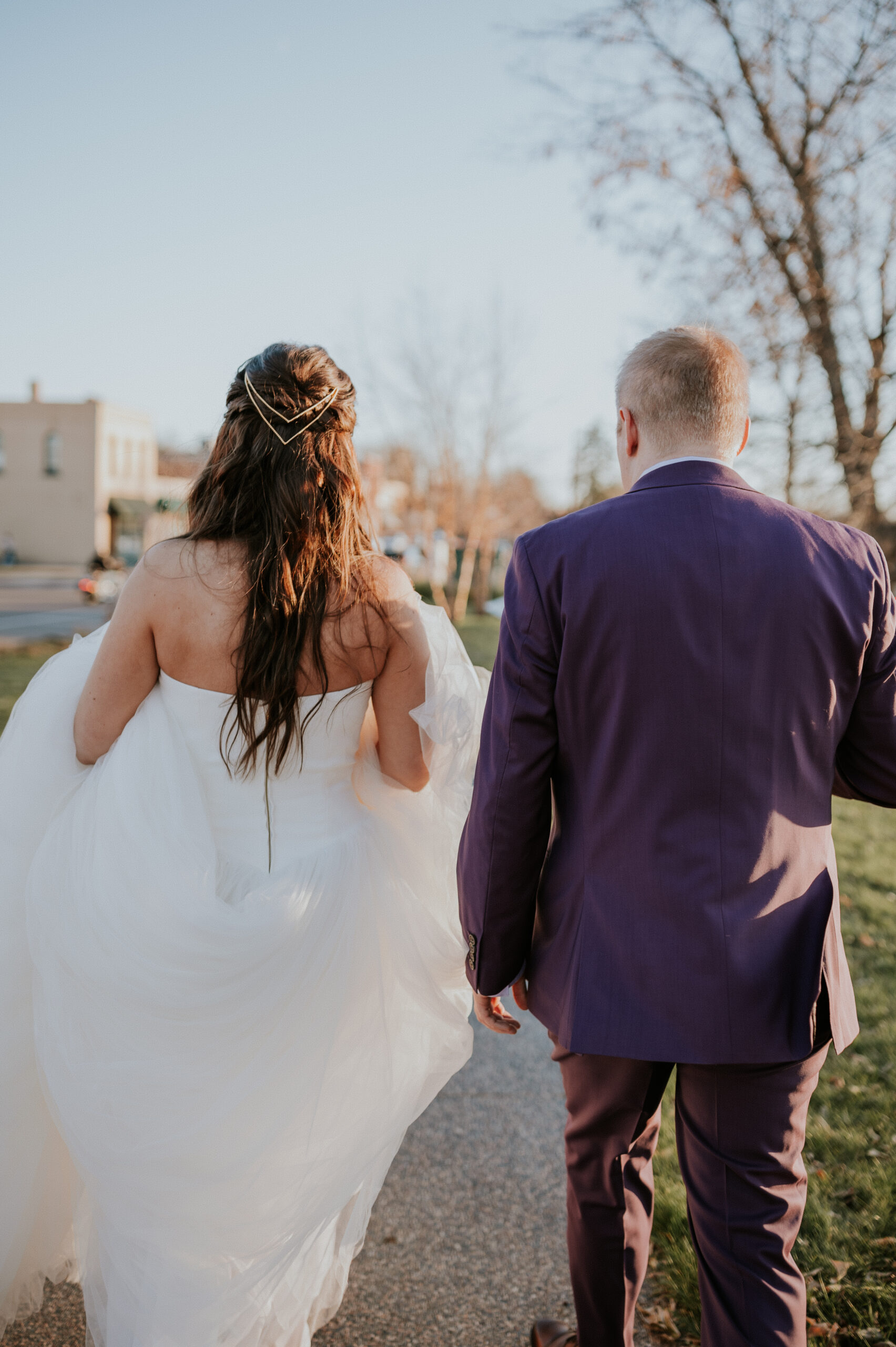 A sweet candid of the couple walking away together, with the bride lifting her dress slightly and the groom by her side.