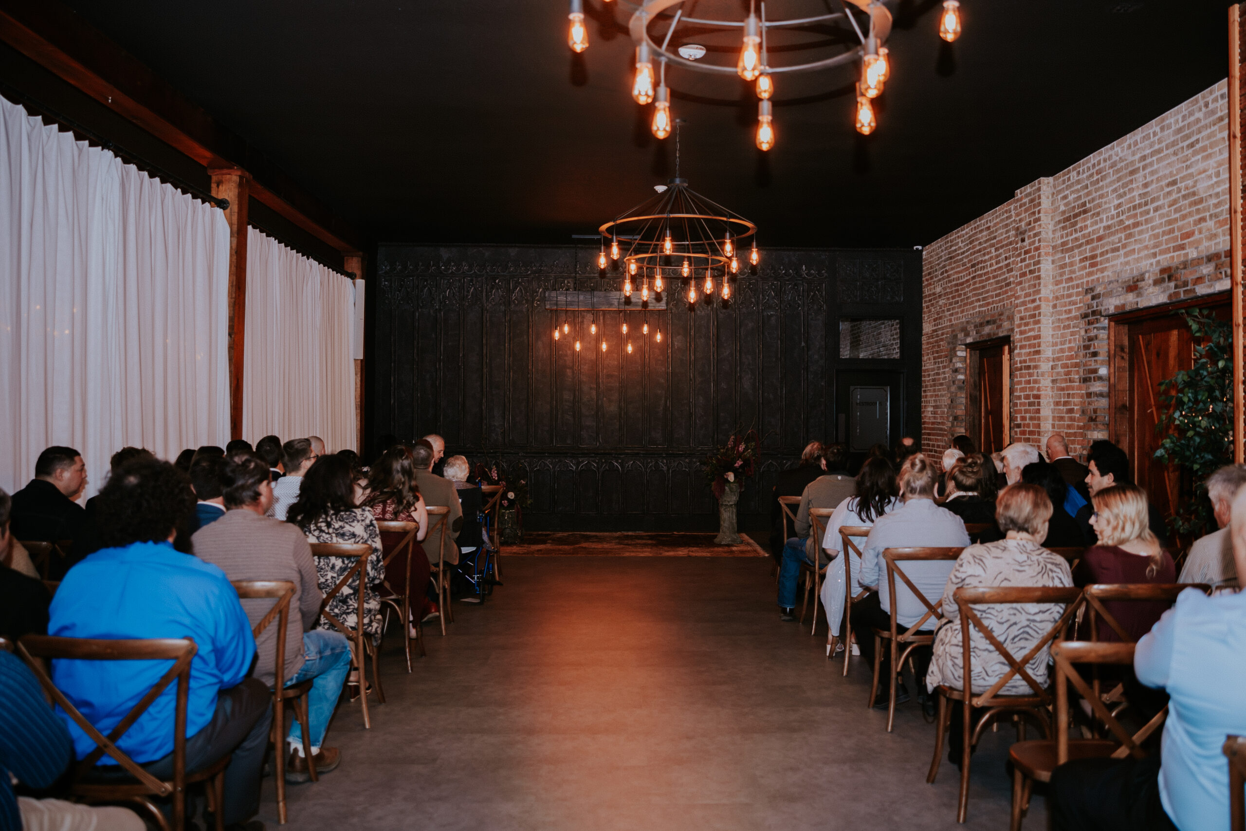 Friends and family fill the rows of a candlelit venue, waiting for the ceremony to begin at this intimate wedding in Minnesota.